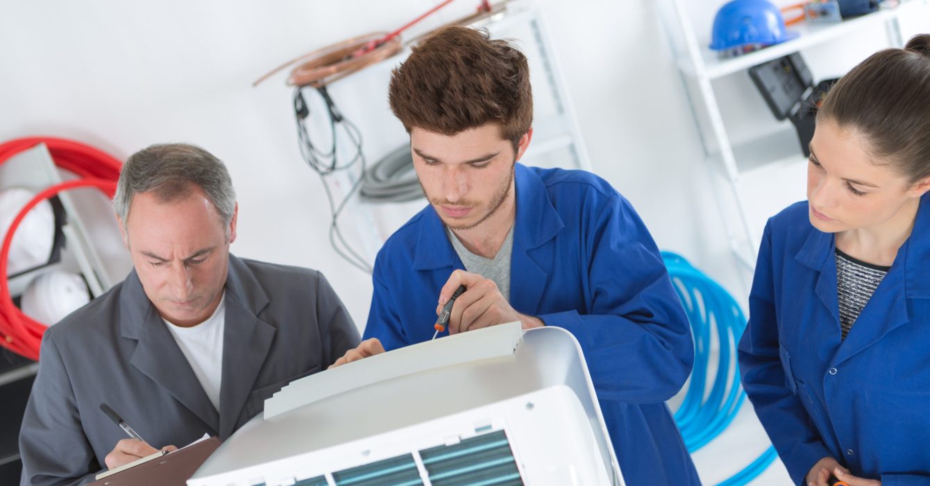 electrician repairman and apprentices fixing air conditioning